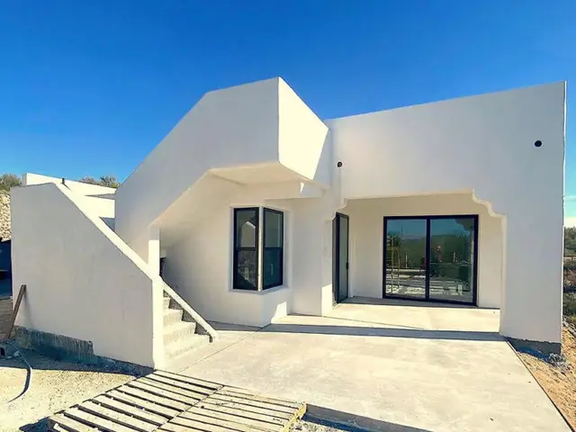 A completed Zenith home with a smooth monolithic sprayed-shell exterior and deep-set window reveals.