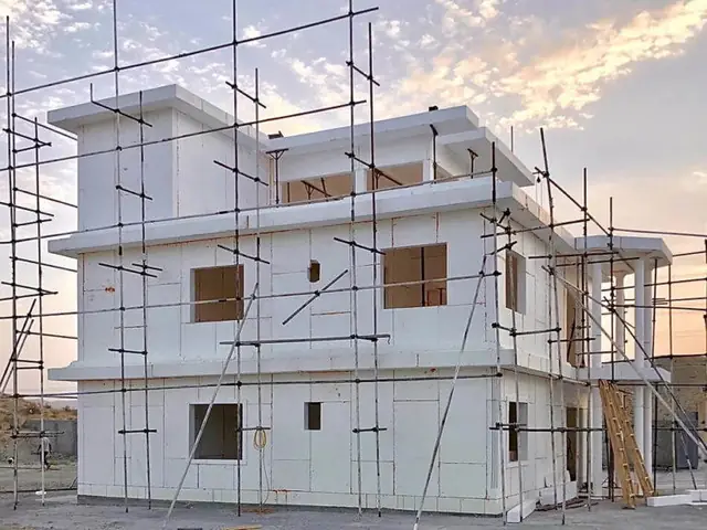 A two-storey Zenith build under scaffold, its expanded-polystyrene panel walls standing before the composite coating is sprayed.