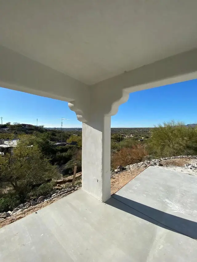 A covered outdoor room on a completed build, its sprayed column meeting the beam above without a layered joint.