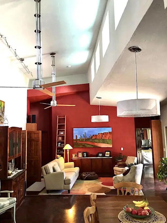 A finished interior with a high vaulted ceiling, a single deep accent wall and framed artwork.